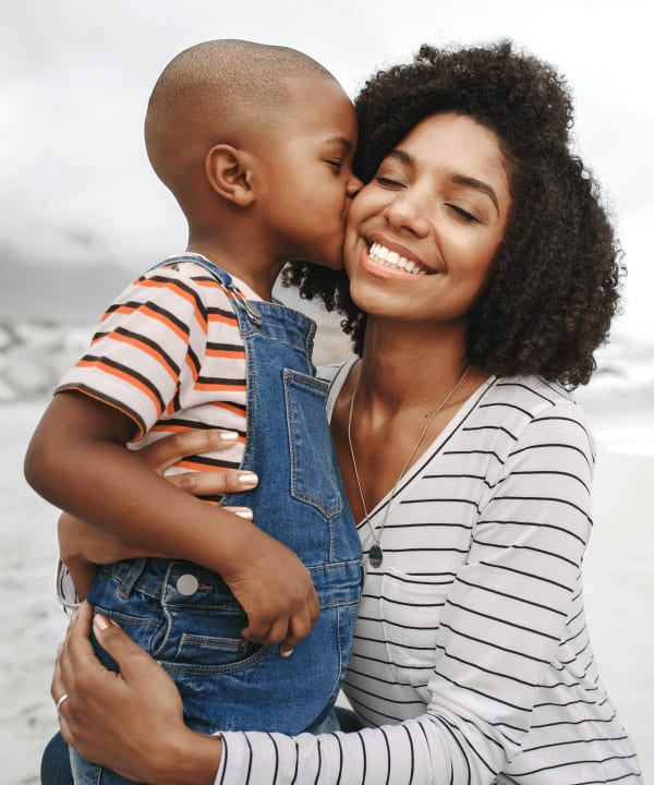 Two young girls are standing outside on a soccer field with an arm around eachother while holding a soccer ball together.